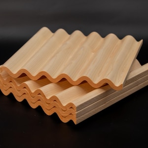 May include: A stack of light-colored wooden soap dishes with a wavy design. The dishes are made of natural wood and have a smooth finish. The wavy design allows for air circulation and drainage.