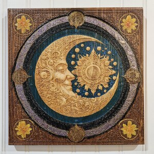 May include: A wooden wall art piece with a carved design of a crescent moon and sun. The moon has a face and the sun has rays. The background is a dark blue with gold and purple accents.