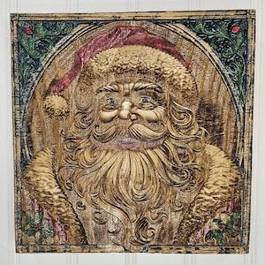 May include: A wooden carved Santa Claus face with a red hat and white beard. The carving is on a wooden background with green and gold accents.