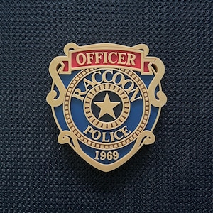May include: A gold, blue, and red police badge with the text "OFFICER RACCOON POLICE 1969" and a gold star in the center. The badge has a shield shape with a gold border and is set against a dark blue textured background.