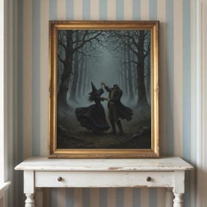 May include: A framed wall art print depicting a headless figure in a dark coat dancing with a figure in a witch hat and black dress within a misty, dark forest. The artwork is enclosed in a gold-toned rectangular frame with ornate detailing.