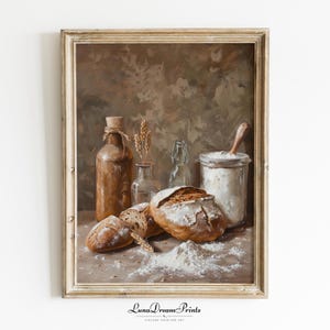 Op de afbeelding: Een ingelijst olieverfschilderij met een rustieke keukenscène met een bruine fles, een glazen pot gevuld met bloem, een houten lepel en twee broden met een knapperige korst. Aren van tarwe en verspreide bloem liggen op het oppervlak. De tekst LunaDreamPrints staat onderaan.