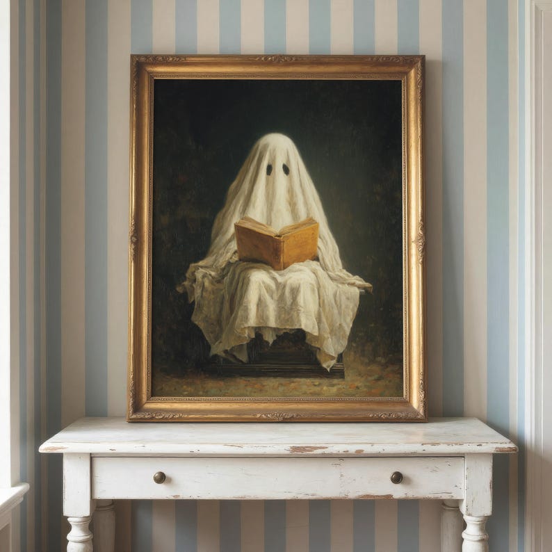 May include: A framed oil painting depicting a figure draped in a white sheet, resembling a ghost, sitting and reading an open tan book. The artwork is enclosed in an ornate gold frame, showcasing a dark, moody background behind the central figure.
