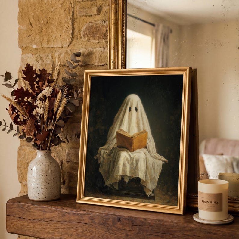 May include: A framed rectangular wall art print featuring a figure draped in a white sheet, resembling a ghost, sitting and reading an open brown book. The artwork is set against a dark, moody background and enclosed in a simple gold frame.