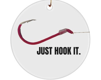 Op de afbeelding: Een witte keramische kerstversiering met een rode vishaak en de tekst "JUST HOOK IT."
