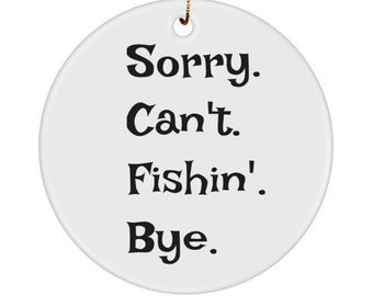 Op de afbeelding: Witte kerstbal van keramiek met zwarte tekst die "Sorry. Can't. Fishin'. Bye." luidt.