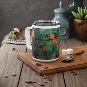 Könnte beinhalten: Eine weiße Keramiktasse mit Henkel. Die Tasse hat ein Design aus einer Collage von grünen und orangefarbenen Leiterplatten.