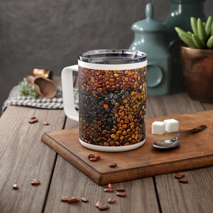 May include: White ceramic coffee mug with a handle. The mug features a design of a close-up of coffee beans in various shades of brown, black, and red.
