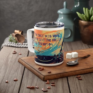May include: White ceramic travel mug with a colorful graphic of a record player and the text "The beat was very dirty and the vocals had distortion".