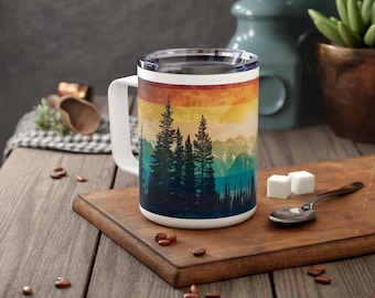 May include: White travel mug with a colorful sunset and silhouette of trees design. The mug has a lid and a handle.