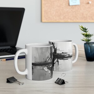 May include: Two white ceramic mugs with black and gray abstract designs. The mugs have a handle on the right side.