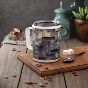 May include: A white ceramic mug with a handle, featuring a camouflage pattern in shades of green, brown, and beige. The mug is sitting on a wooden surface.