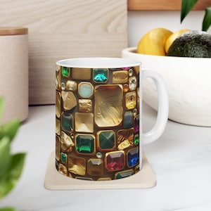 Puede incluir: Taza de cerámica blanca con un diseño colorido de oro y piedras preciosas de varios colores. La taza tiene un asa en el lado derecho.