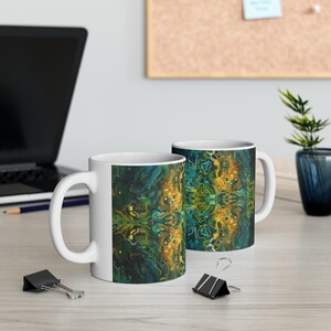 May include: Two white ceramic mugs with a colorful abstract design. The design features a pattern of green, blue, and yellow lines and shapes, resembling a circuit board.