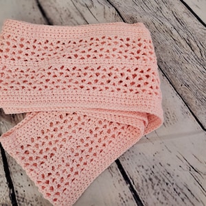 May include: A pink crocheted scarf with a delicate openwork pattern.