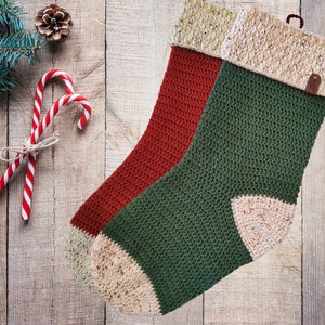 May include: Two crocheted Christmas stockings, one red and one green, with a beige cuff. The stockings are hanging on a wooden background.