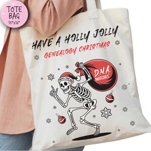 以下が含まれることがあります： 「HAVE A HOLLY JOLLY GENEALOGY CHRISTMAS」の文字が入ったクリーム色のトートバッグ。サンタ帽をかぶった骸骨が「D.N.A. MATCHES」と書かれた赤いバッグを持っています。バッグのサイズは約38cm x 41cmです。雪の結晶とオーナメントがバッグを飾っています。