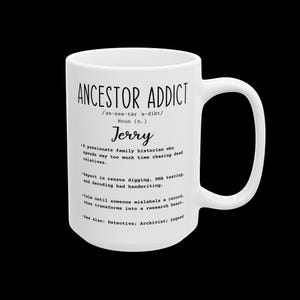 May include: A white ceramic mug featuring black text that defines the term Ancestor Addict. The text includes a phonetic pronunciation, the name Jerry, and a humorous description of a family historian who enjoys census digging and DNA testing.