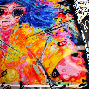 May include: A vibrant, colorful artwork featuring a stylized portrait with blue hair and large black sunglasses. The painting is filled with bright hues of orange, yellow, pink, and blue, with the text "velvet toad ART" in the upper right corner.