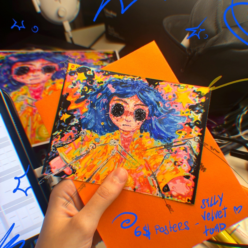 May include: A colorful art print featuring a character with blue hair and black eyes, wearing a yellow coat. The print is held over an orange envelope. Text on the envelope reads "6$ Posters - Silly Velvet - toad."
