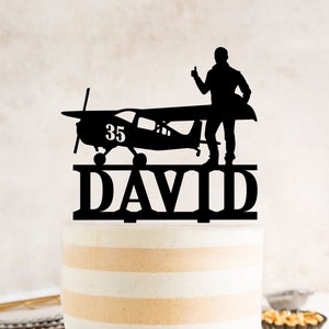 a cake with a silhouette of a man standing on top of a plane