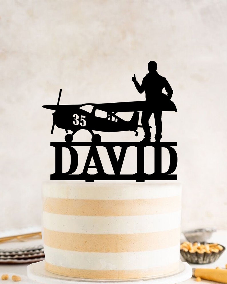 a cake with a silhouette of a man standing on top of a plane