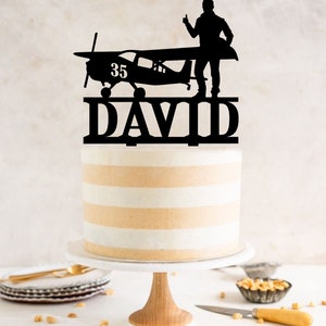 a cake with a silhouette of a man standing on top of a plane