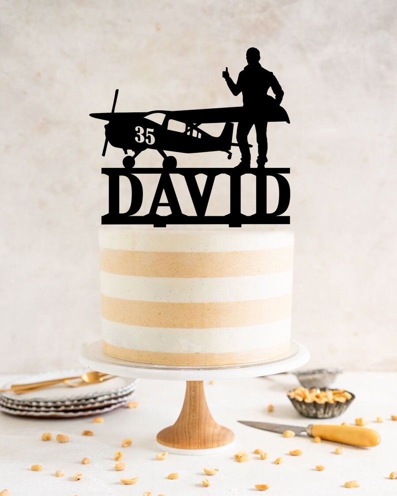 a cake with a silhouette of a man standing on top of a plane