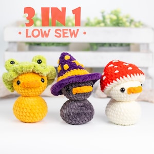 May include: Three crocheted amigurumi duck plushies with different hats. The first duck is wearing a green frog hat, the second duck is wearing a purple and yellow witch hat, and the third duck is wearing a red and white mushroom hat. The caption reads "3 IN 1 - LOW SEW."