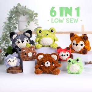 Peut inclure: Six peluches en crochet amigurumi d'animaux : un loup, une grenouille, un renard, un ours, un raton laveur et une autre grenouille. Les peluches sont toutes petites et ont de grands yeux. Les peluches sont disposées sur une surface blanche avec le texte « 6 IN 1 - LOW SEW - » au-dessus.