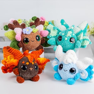 May include: Four handmade crochet plush creatures in various colors. One is brown with orange and yellow accents, another is teal, and a third is light blue with white accents. The fourth is brown with green, pink, and blue accents. Each has large, expressive eyes.