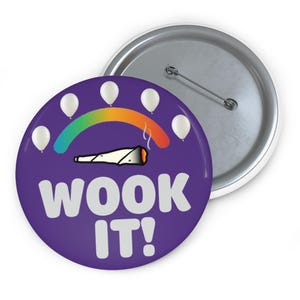 May include: A purple button with the text "WOOK IT!" in white. The button features a rainbow arc, white balloons, and a graphic of a lit joint. The back of the button is silver.