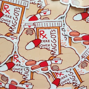 Puede incluir: Una colección de pegatinas con un perezoso de dibujos animados sosteniendo una botella de píldoras con el texto "Rx Maggots Take Once A Day". El perezoso lleva un gorro de enfermera y tiene un corazón en el pecho. Las pegatinas están impresas en papel blanco con un acabado brillante.