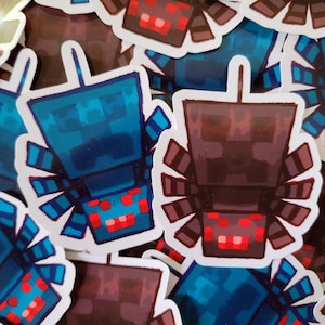Può includere: Una collezione di adesivi con un design di insetto pixelato. Gli adesivi hanno un bordo bianco e sono principalmente blu e marroni con accenti rossi. L'insetto ha una testa quadrata e più zampe.
