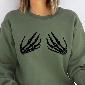May include: A green sweatshirt with a black skeleton hand graphic on the front.