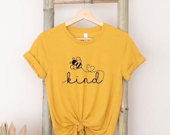 May include: A yellow t-shirt with a black bee and heart design and the word "kind" printed on it.