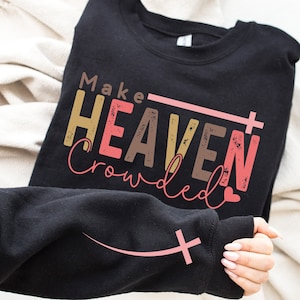 May include: Black sweatshirt with the text "Make Heaven Crowded" in pink, brown, and gold lettering with a pink cross and heart.