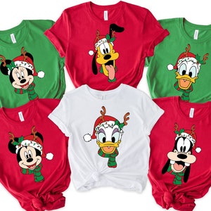 May include: Six red, green, and white t-shirts with different Disney characters wearing Santa hats and reindeer antlers. The characters include Mickey Mouse, Minnie Mouse, Donald Duck, Goofy, and Daisy Duck.