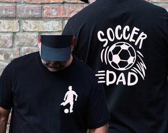 Könnte beinhalten: Zwei schwarze T-Shirts mit weißem Text und Grafiken. Ein Shirt sagt "Soccer Dad" mit einem Fußball-Motiv. Das andere Shirt zeigt eine Silhouette eines Fußballspielers, der einen Ball tritt.