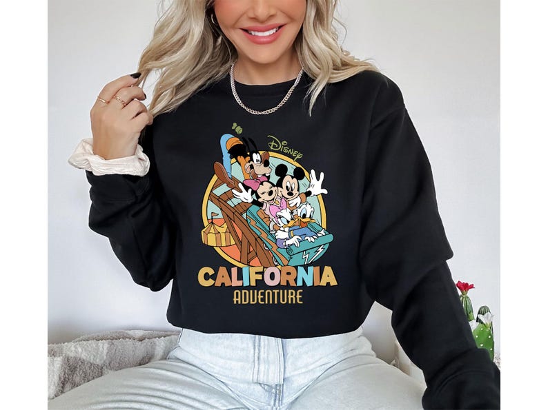 May include: Black sweatshirt featuring a colorful graphic of Disney characters on a ride, with the words "Disney California Adventure" in a retro font. The sweatshirt is a crew neck style.