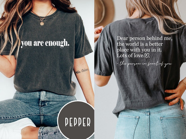 Pu&ograve; includere: Due magliette grigie con testo bianco. La maglietta anteriore dice "you are enough." La maglietta posteriore dice "Cara persona dietro di me, il mondo &egrave; un posto migliore con te dentro. Tanto amore." - la persona davanti a te.