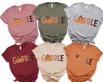 May include: A collection of six short-sleeved t-shirts in various colors, each featuring the word "GOBBLE" with a cartoon turkey character. The shirts are in shades of pink, green, gray, burgundy, beige, and orange.