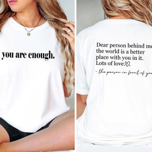 Pu&ograve; includere: Maglietta bianca con la scritta "you are enough." sul davanti e la scritta "Dear person behind me, the world is a better place with you in it. Lots of love. - the person in front of you" sul retro.