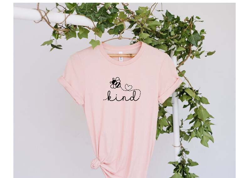 May include: A pink t-shirt with a black bee and heart design and the word "kind" printed on it.