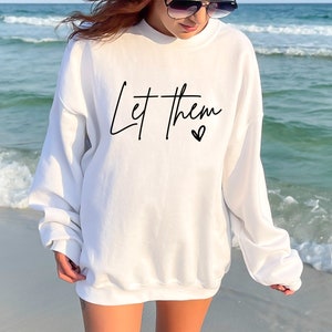 May include: White sweatshirt with the text "Let them" in black script with a small heart symbol.