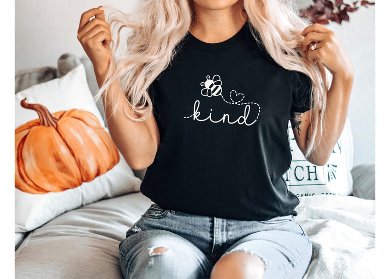 May include: Black t-shirt with a white bee and flower graphic and the text "be kind" in a cursive font.