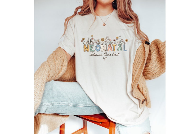 May include: A white t-shirt with a floral design and the text "NEONATAL Intensive Care Unit" in colorful letters.