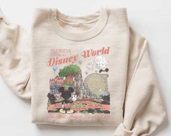 Może przedstawiać: Beżowa bluza z okrągłym dekoltem i nadrukiem graficznym przedstawiającym Disney World na Florydzie. Wzór zawiera Myszkę Miki, zamek, kulę Epcot oraz napis Florida Est. 1971 Disney World The Most Magical Place On Earth.