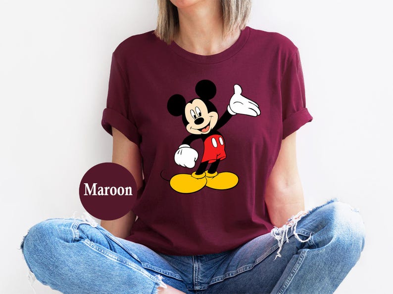 Puede incluir: Camiseta granate con un gr&aacute;fico de Mickey Mouse. Mickey se muestra con orejas negras, cuerpo negro, guantes blancos, pantalones cortos rojos y zapatos amarillos. La camiseta es de color granate liso.