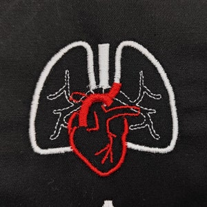 Pu&ograve; includere: Toppa ricamata con un cuore rosso e polmoni bianchi su sfondo nero. Il cuore &egrave; dettagliato con cuciture rosse e i polmoni sono delineati in bianco. Ideale per professionisti medici o appassionati di anatomia.
